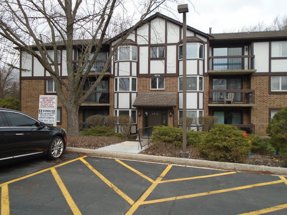 Front view of a multi-story apartment building with brick facade and large windows.