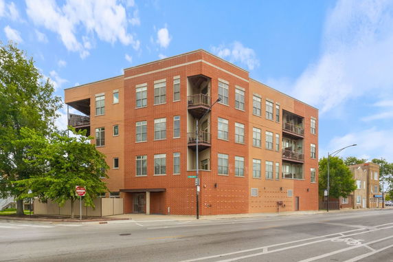Front view of a multi-story brick building on a street corner.
