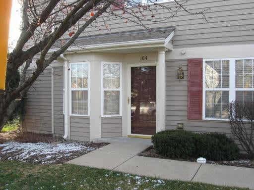 Front view of a house with beige siding and a red shutter.