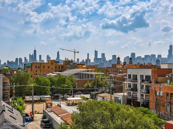 Panoramic view of a city skyline with various buildings and construction cranes.