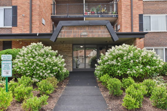 Front view of a multi-story brick building entrance with plants.