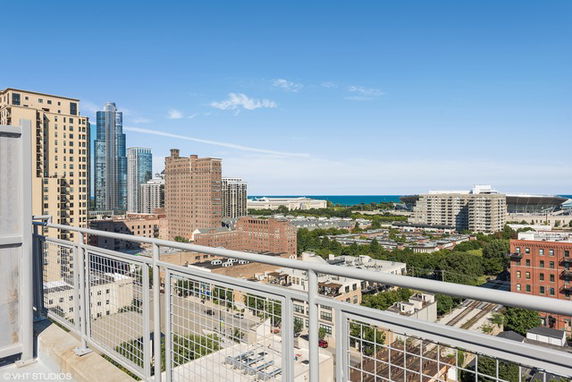 Panoramic view from a building balcony showing cityscape and distant lake.