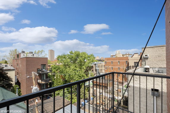 Panoramic view of cityscape with buildings and trees from a balcony.