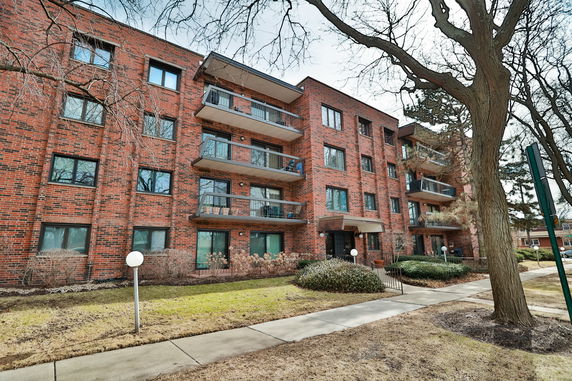 Front view of a multi-story brick apartment building with balconies.