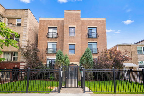 Front view of a three-story brick apartment building with decorative balconies.