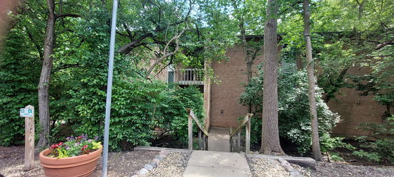 Front view of a brick building partially obscured by trees and greenery.