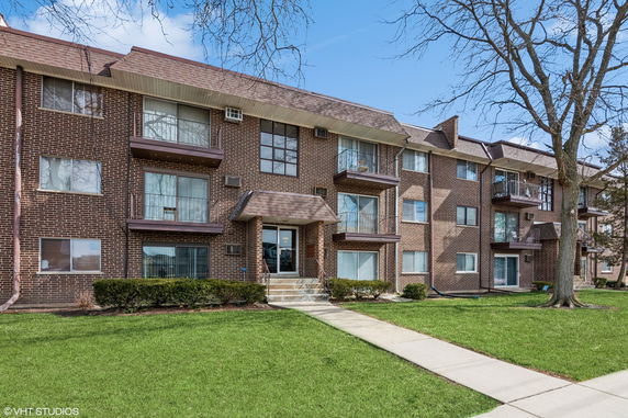 Front view of a multi-story brick apartment building with balconies.
