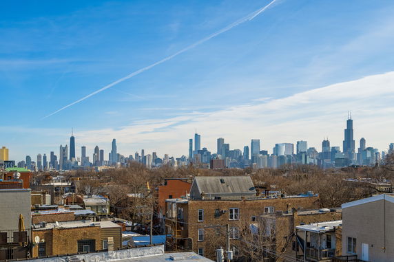 Wide view of a city skyline with various tall buildings and a clear blue sky.