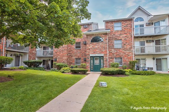 Front view of a multi-story brick apartment building with balconies and green entrance door.