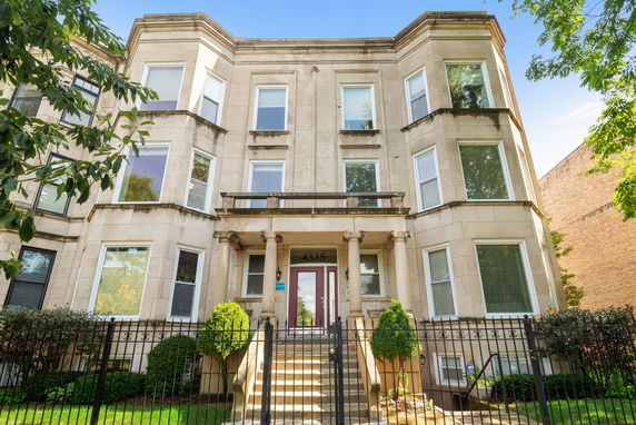 Front view of a multi-story residential building with a gated entrance.