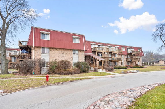 Front view of a multi-story residential building with a red roof and balconies.