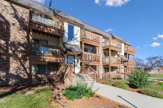 Front view of a multi-story brick apartment building with wooden balconies.
