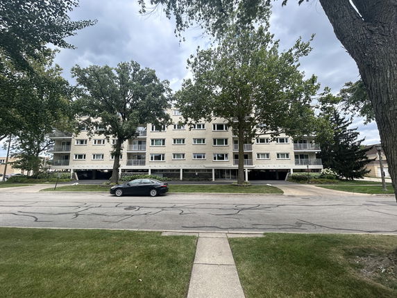 Front view of a multi-story residential building with parking area.