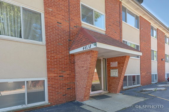 Front view of a multi-story apartment building with brick facade and entrance canopy.