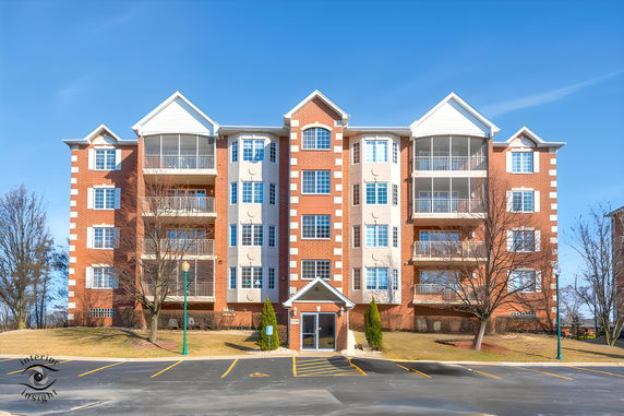 Front view of a multi-story apartment building with brick facade and multiple balconies.