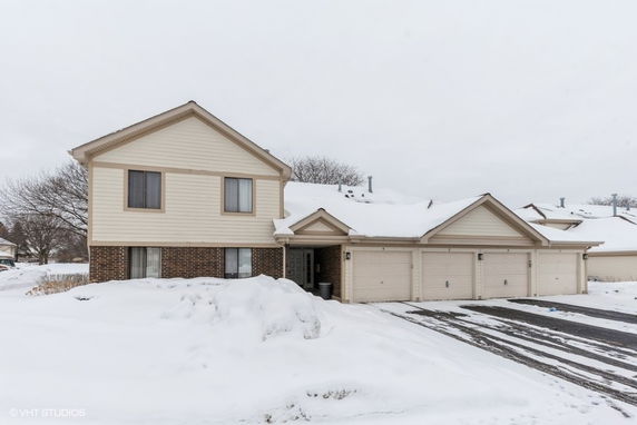 Front view of a two-story house with a three-car garage in a snowy setting.