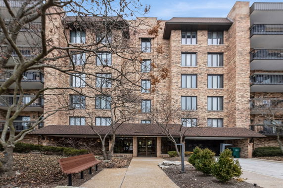 Front view of a multi-story brick building with balconies and entrance walkway.
