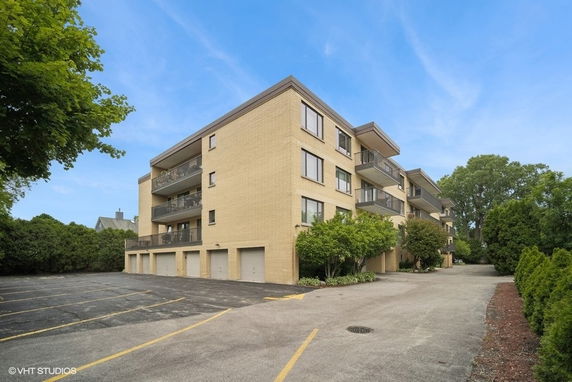 Front view of a multi-story apartment building with balconies and garages.