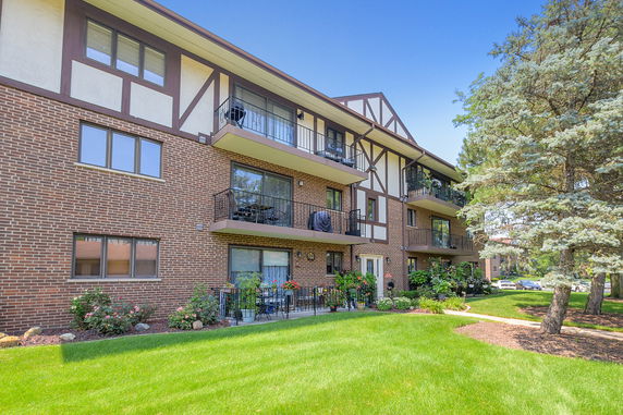 Front view of a three-story apartment building with brick exterior and balconies.