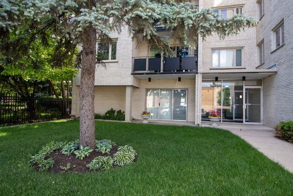 Front view of a multi-story residential building with a glass entrance and balconies.