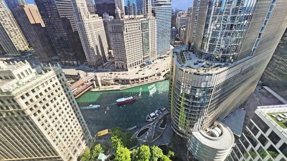 Panoramic view of a cityscape with tall buildings and a river in the foreground.