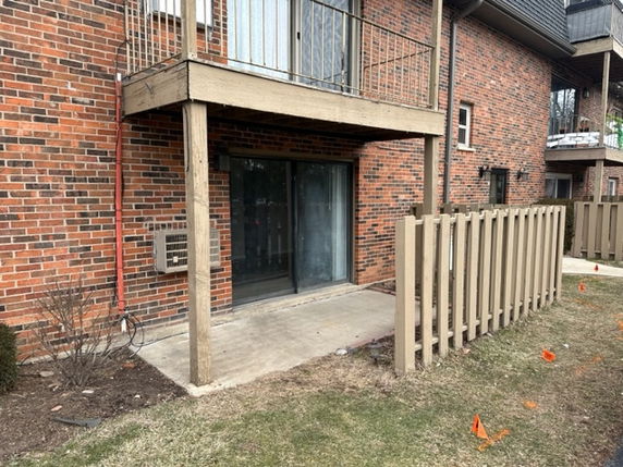 Brick apartment building with a small patio and balcony.