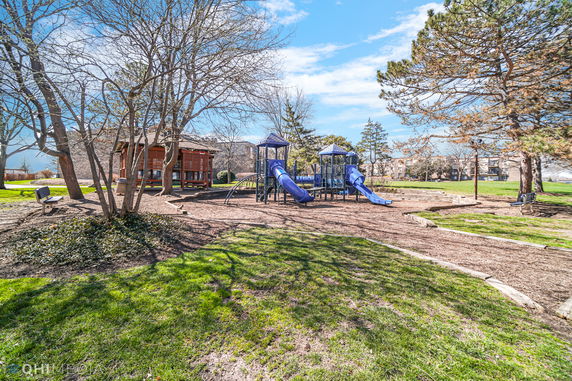 Children's playground with slides and climbing structures surrounded by trees.