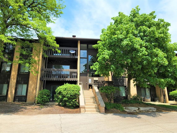 Front view of a multi-story residential building with balconies and trees.