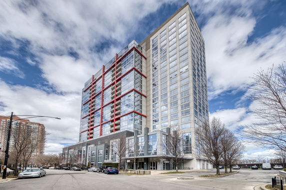 Front view of a multi-story modern residential building with large windows and red accents.