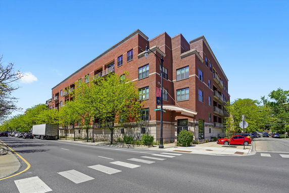 Front view of a multi-story brick building on a street corner.