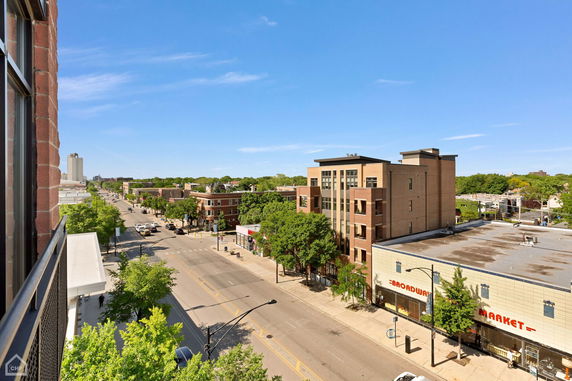 Panoramic view of a street lined with buildings and trees, seen from an elevated perspective.