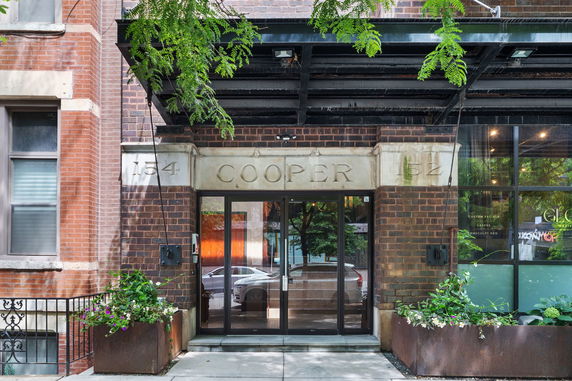 Front view of a building entrance with large glass doors and brick exterior.