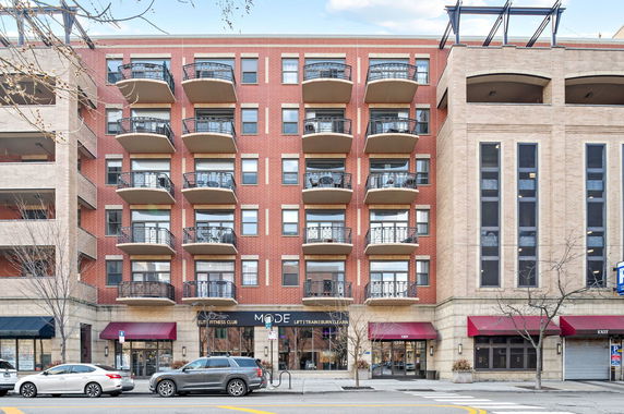 Front view of a multi-story building with balconies and storefronts.