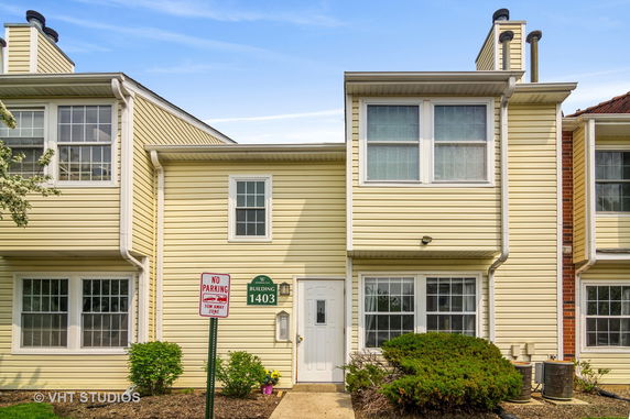 Front view of a two-story residential building with yellow siding and a white entrance door.