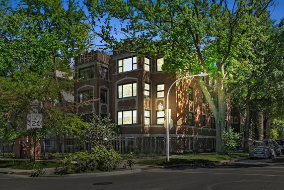 Front view of a multi-story brick building with large windows.