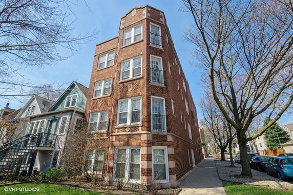 Front view of a multi-story brick apartment building with large windows.