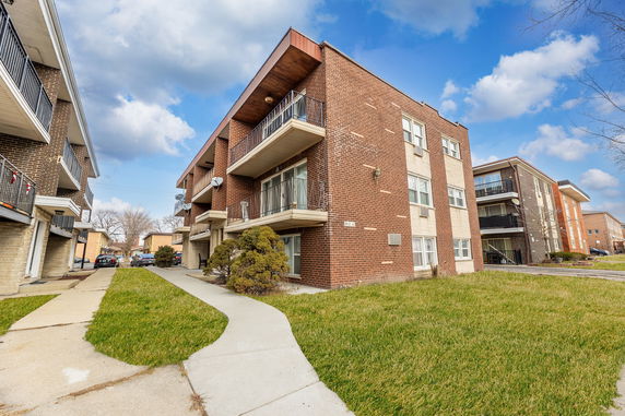 Front view of a multi-story brick apartment building with multiple balconies.