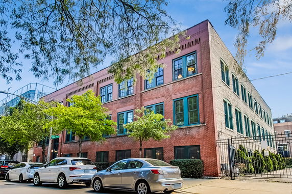 Front view of a three-story brick building with blue window frames.