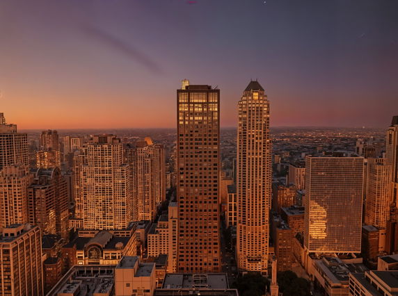 Panoramic view of city skyline with tall buildings at sunset.