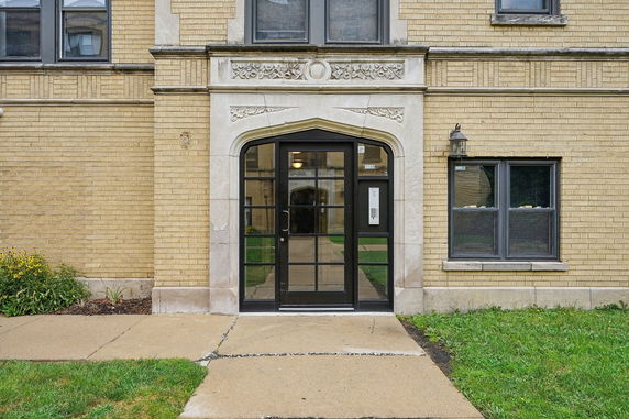 Front view of a building entrance with decorative stone arch and glass door.