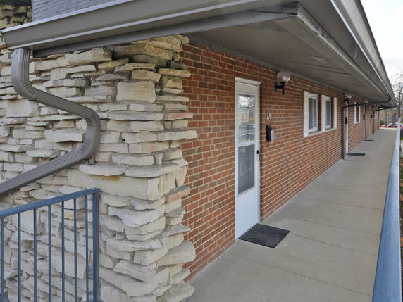 Side view of a multi-unit building with brick walls and stone accents.