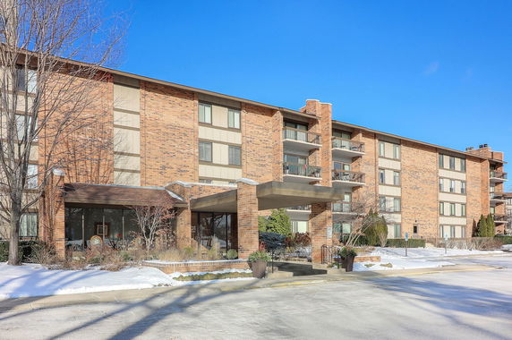 Front view of a multi-story brick apartment building with balconies.