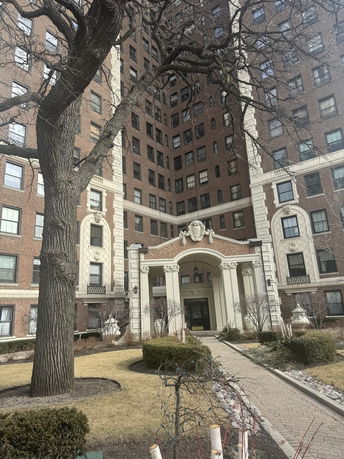Front view of a multi-story brick apartment building with a central archway entrance.