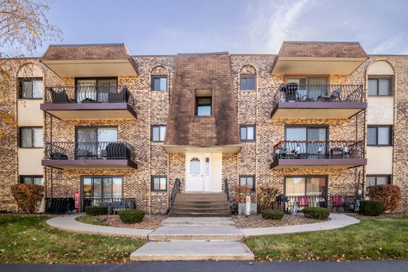 Front view of a multi-story brick apartment building with balconies.