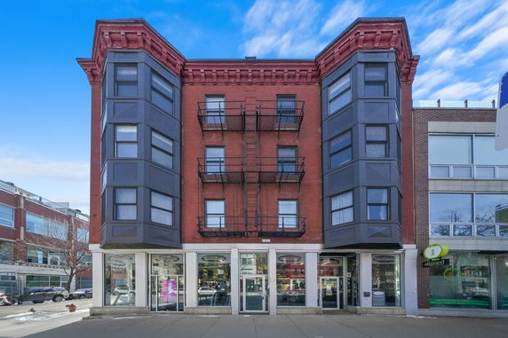 Front view of a multi-story brick building with bay windows.