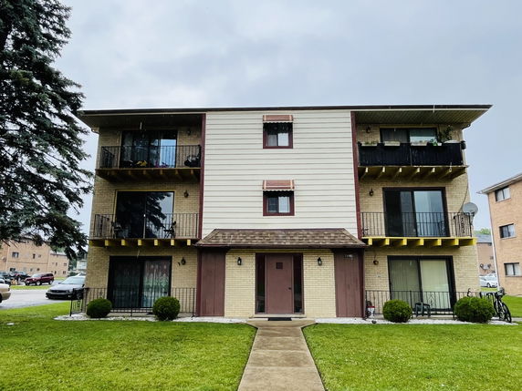 Front view of a three-story apartment building with balconies.