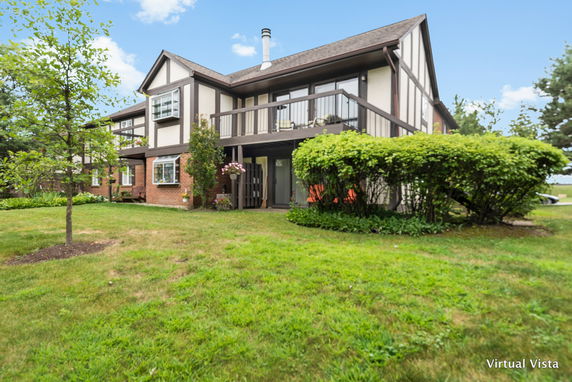 Front view of a two-story house with a balcony and wood accents.
