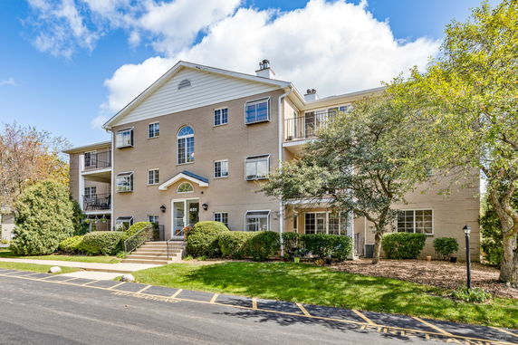 Front view of a multi-story residential building with brick exterior and balconies.