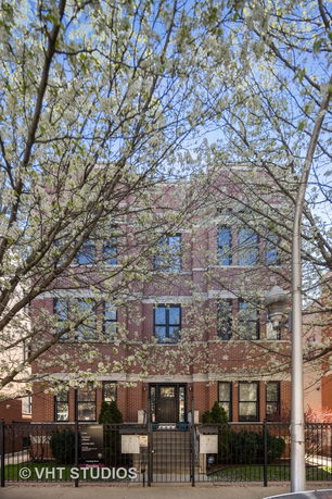 Front view of a three-story brick building with a gated entrance.