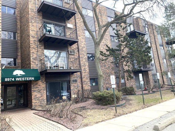 Front view of a multi-story residential building with balconies and brick facade.